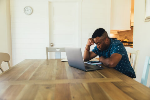 Unemployed man look at finances on computer.